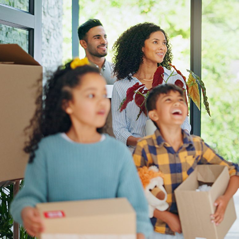 Young married couple carrying cardboard box in front of their new home on moving day Young married couple carrying cardboard box in front of their new house on moving day